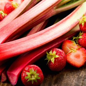 Fresh rhubarb and strawberries on a wooden underground